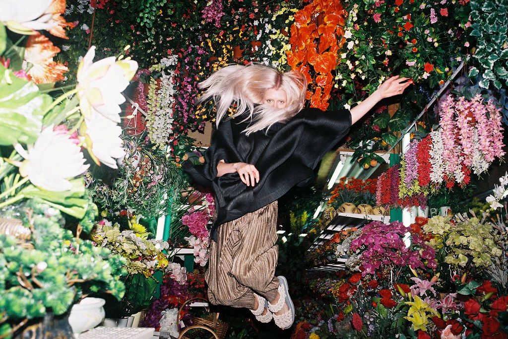 An artistic film photograph of a woman surrounded by flowers, by Lukasz Wierzbowski, featured in Variant Journal.